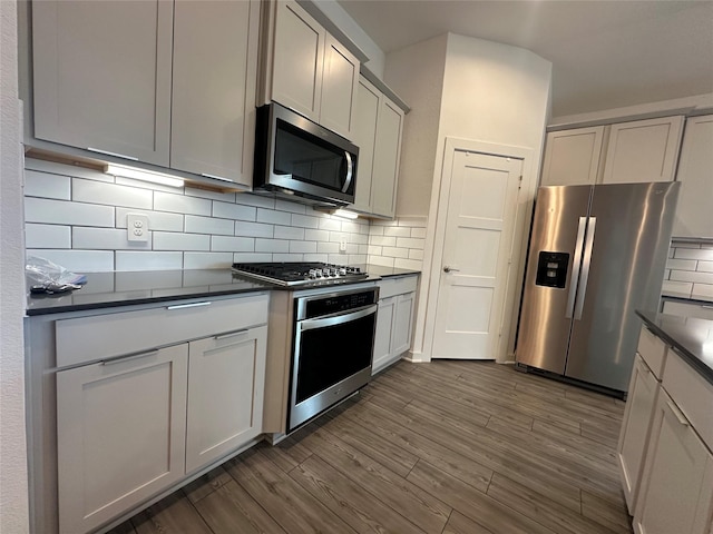 14007 Valley Creek Ct, Conroe, TX 77384 - kitchen featuring stainless steel appliances, dark countertops, dark wood finished floors, and tasteful backsplash