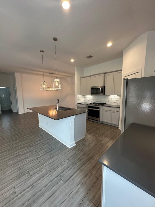 14007 Valley Creek Ct, Conroe, TX 77384 - kitchen featuring appliances with stainless steel finishes, dark countertops, a sink, tasteful backsplash, and dark wood-style floors