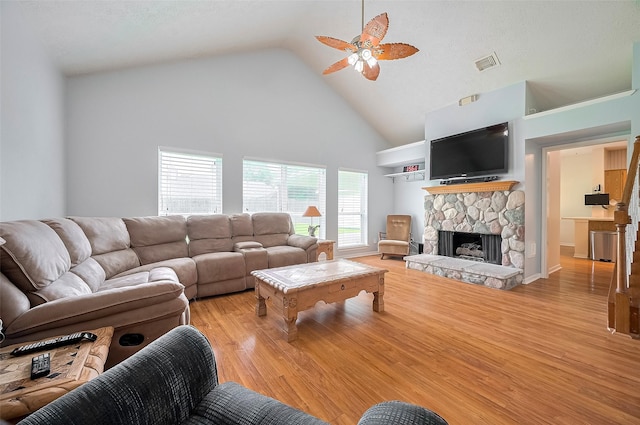 20011 Doherty Cir, Katy, TX 77449 - living room featuring high vaulted ceiling, a ceiling fan, a stone fireplace, and light wood-type flooring