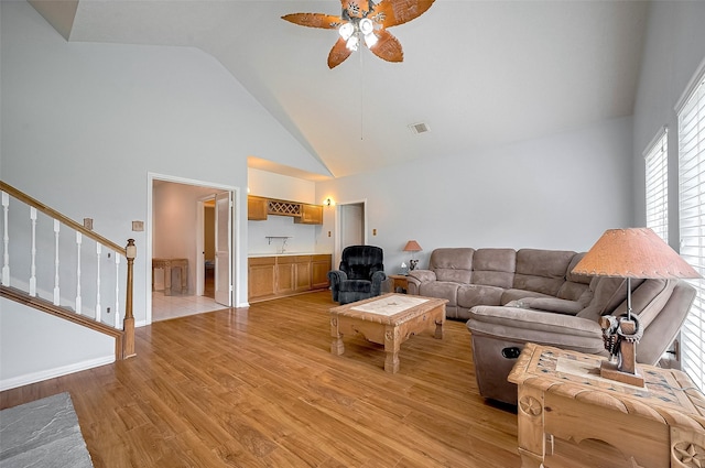 20011 Doherty Cir, Katy, TX 77449 - living area featuring ceiling fan, light wood-type flooring, stairs, high vaulted ceiling, and a wainscoted wall