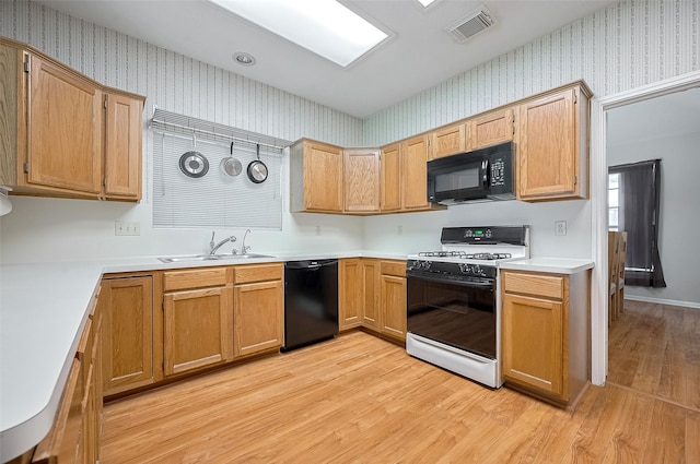 20011 Doherty Cir, Katy, TX 77449 - kitchen with black appliances, a sink, wallpapered walls, light wood-style floors, and light countertops
