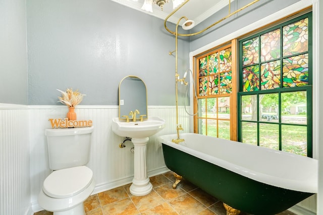 411 Southern Oaks Dr, Lake Jackson, TX 77566 - bathroom featuring a soaking tub, toilet, a wainscoted wall, and tile patterned flooring