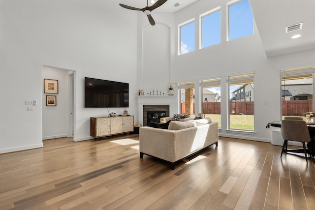 24407 Green Buffalograss Trl, Katy, TX 77493 - living area with ceiling fan, a high ceiling, a glass covered fireplace, wood finished floors, and baseboards