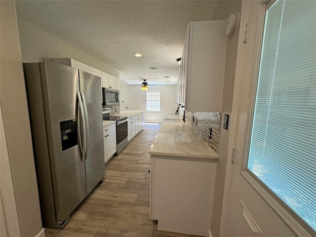 10 Walnut Loop, Shepherd, TX 77371 - kitchen with appliances with stainless steel finishes, a ceiling fan, white cabinets, wood finished floors, and a textured ceiling