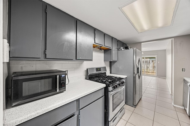 1043 Sierra Shadows Dr, Katy, TX 77450 - kitchen featuring appliances with stainless steel finishes, gray cabinetry, light tile patterned floors, light countertops, and backsplash