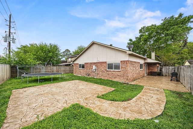 1043 Sierra Shadows Dr, Katy, TX 77450 - back of property with brick siding, a patio area, a trampoline, and a chimney