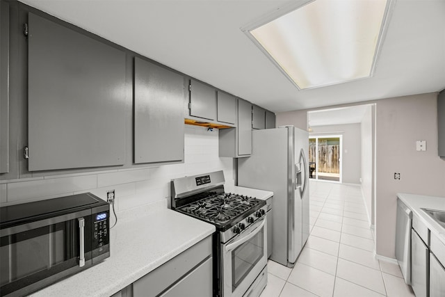 1043 Sierra Shadows Dr, Katy, TX 77450 - kitchen with appliances with stainless steel finishes, gray cabinets, light tile patterned floors, and light countertops