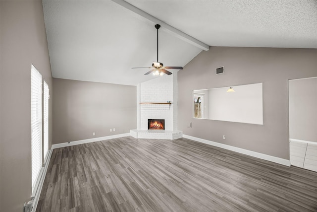 1043 Sierra Shadows Dr, Katy, TX 77450 - unfurnished living room featuring ceiling fan, beam ceiling, a fireplace, wood finished floors, and high vaulted ceiling