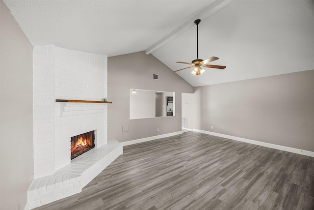 1043 Sierra Shadows Dr, Katy, TX 77450 - unfurnished living room featuring ceiling fan, beamed ceiling, wood finished floors, a fireplace, and baseboards