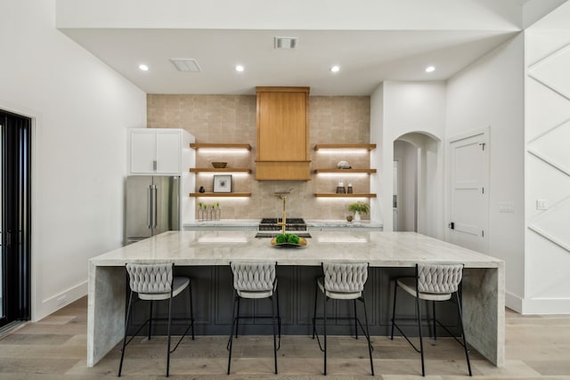 7310 Jalna St, Houston, TX 77055 - kitchen with high quality fridge, open shelves, a large island with sink, backsplash, and light wood-type flooring