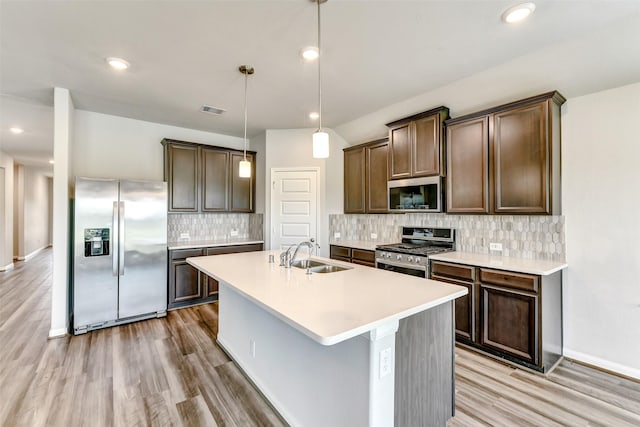 1210 Oak Barrel Run, Richmond, TX 77406 - kitchen with appliances with stainless steel finishes, a sink, light wood-type flooring, a center island with sink, and dark brown cabinets