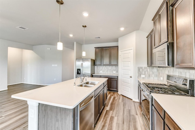 1210 Oak Barrel Run, Richmond, TX 77406 - kitchen with stainless steel appliances, a sink, light wood-style floors, decorative backsplash, and light countertops