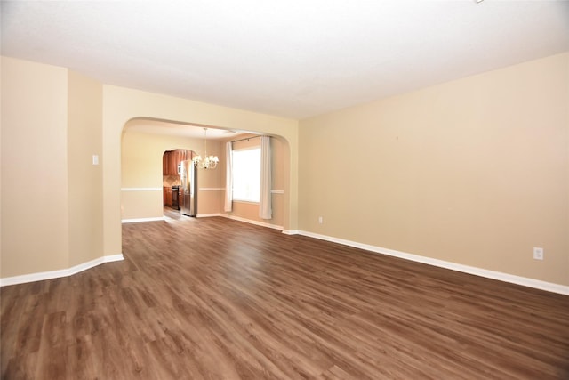 9619 Babbling Spring Ct, Tomball, TX 77375 - spare room with arched walkways, a chandelier, dark wood-style floors, and baseboards