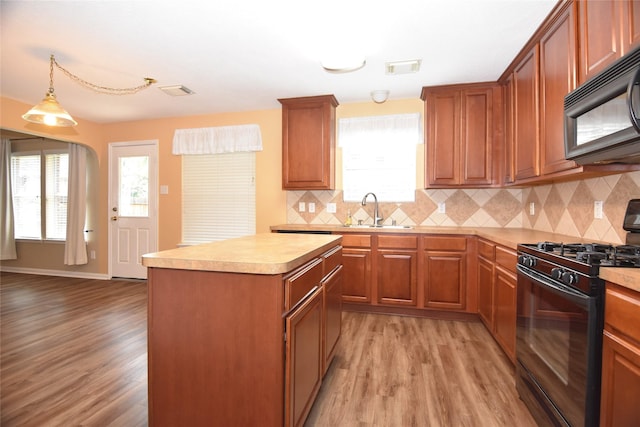 9619 Babbling Spring Ct, Tomball, TX 77375 - kitchen with black appliances, a sink, light wood-type flooring, and a kitchen island
