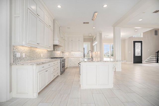11503 Kings Point Blvd, Mont Belvieu, TX 77535 - kitchen featuring high end stove, backsplash, light stone countertops, white cabinetry, and recessed lighting