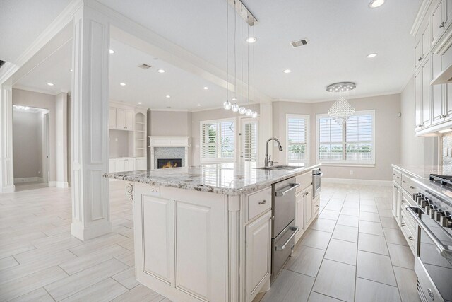 11503 Kings Point Blvd, Mont Belvieu, TX 77535 - kitchen featuring a sink, crown molding, baseboards, a lit fireplace, and a center island with sink
