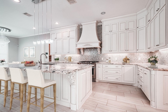 11503 Kings Point Blvd, Mont Belvieu, TX 77535 - kitchen featuring high end stove, custom exhaust hood, a sink, tasteful backsplash, and ornamental molding