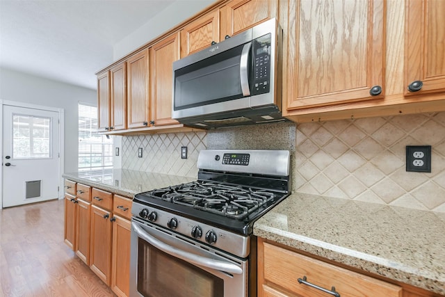 4614 Russett Pl S, Pearland, TX 77584 - kitchen with appliances with stainless steel finishes, light wood-style floors, light stone countertops, and backsplash