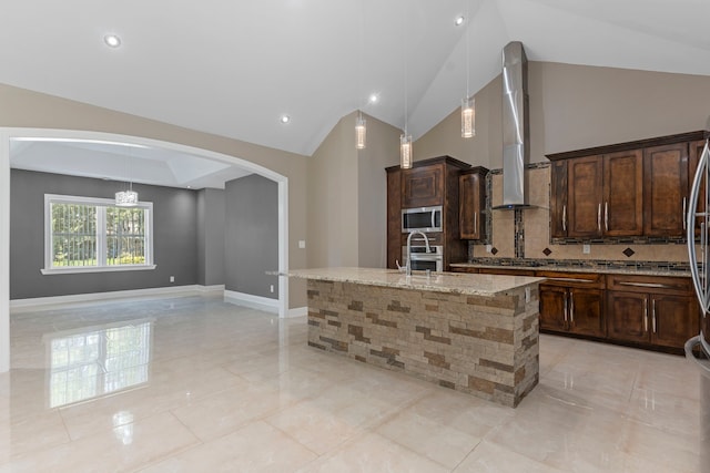 17501 Julianne Dr, Waller, TX 77484 - kitchen featuring appliances with stainless steel finishes, lofted ceiling, arched walkways, light stone countertops, and decorative backsplash
