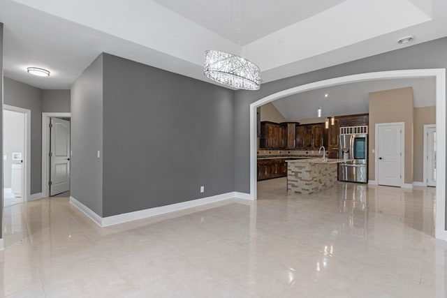 17501 Julianne Dr, Waller, TX 77484 - unfurnished living room featuring arched walkways, a sink, light tile patterned flooring, baseboards, and a chandelier