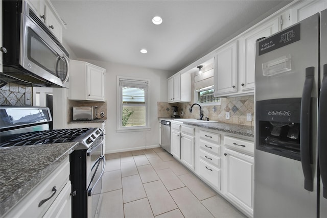 1635 Althea Dr, Houston, TX 77018 - kitchen with stainless steel appliances, a sink, tasteful backsplash, light tile patterned flooring, and white cabinetry