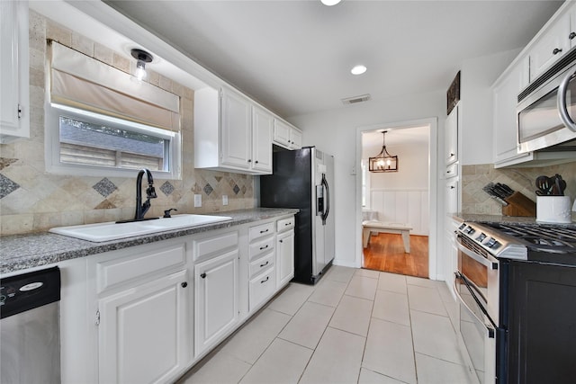 1635 Althea Dr, Houston, TX 77018 - kitchen featuring stainless steel appliances, a sink, white cabinets, and a wainscoted wall