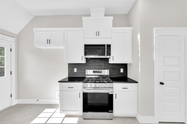 8714 Clarington St, Houston, TX 77016 - kitchen with stainless steel appliances, decorative backsplash, white cabinets, and vaulted ceiling