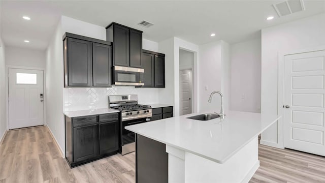 12316 Frisco Cove Ct, Houston, TX 77047 - kitchen with appliances with stainless steel finishes, a sink, light wood-type flooring, a center island with sink, and recessed lighting