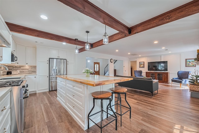 2906 Laurel Fork Dr, Houston, TX 77339 - kitchen with stainless steel appliances, a kitchen breakfast bar, light wood-type flooring, beamed ceiling, and white cabinets
