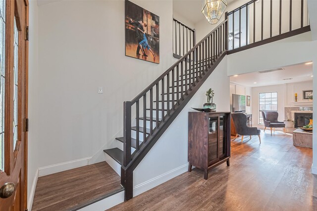 2906 Laurel Fork Dr, Houston, TX 77339 - staircase featuring baseboards, wood finished floors, a chandelier, and a glass covered fireplace