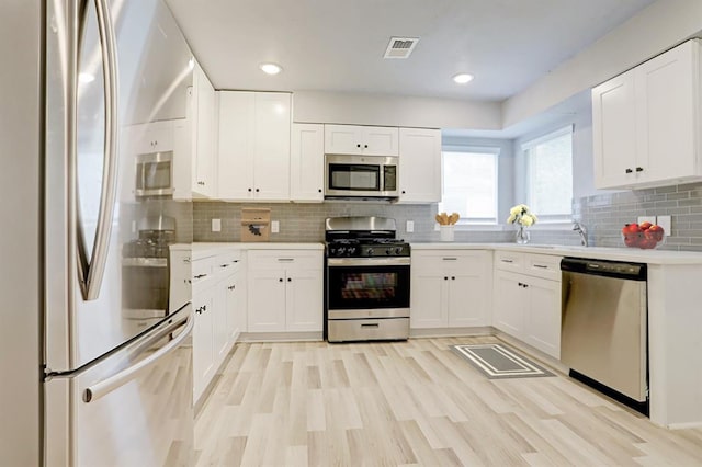 4523 Keystone St, Houston, TX 77021 - kitchen with stainless steel appliances, light countertops, backsplash, light wood-style flooring, and white cabinets