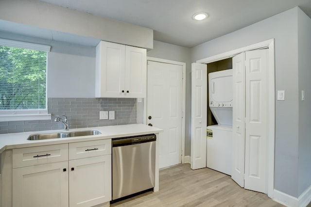 4523 Keystone St, Houston, TX 77021 - kitchen with dishwasher, stacked washer / dryer, a sink, light wood-style flooring, and white cabinetry