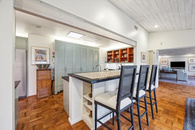 6500 Bayou Front, Galveston, TX 77551 - kitchen featuring open shelves, dark countertops, a breakfast bar area, open floor plan, and wooden ceiling