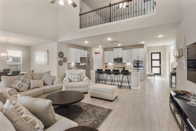 5010 Trembling Aspen Ln, Rosenberg, TX 77471 - living room featuring a chandelier, a towering ceiling, a ceiling fan, light wood finished floors, and recessed lighting