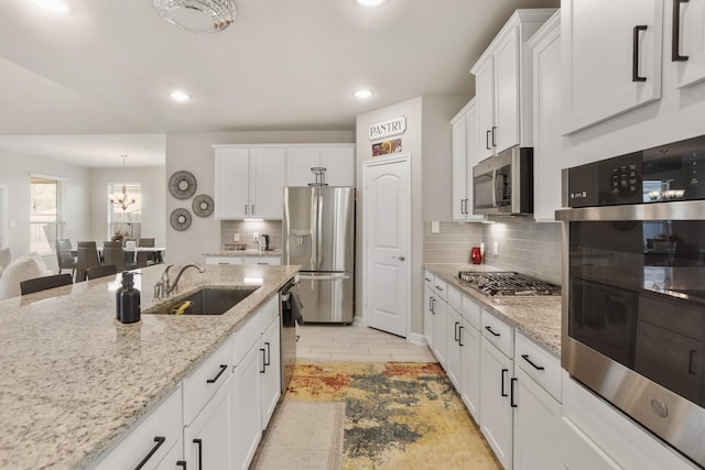 5010 Trembling Aspen Ln, Rosenberg, TX 77471 - kitchen featuring appliances with stainless steel finishes, a sink, recessed lighting, white cabinets, and a chandelier