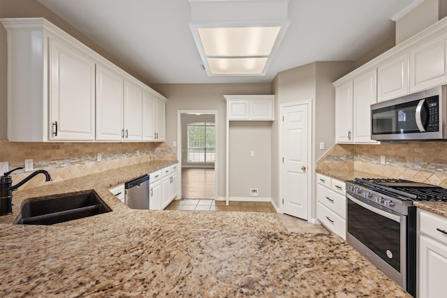 2100 Williams Glen Dr, Bryan, TX 77808 - kitchen featuring appliances with stainless steel finishes, a sink, light stone counters, and white cabinetry