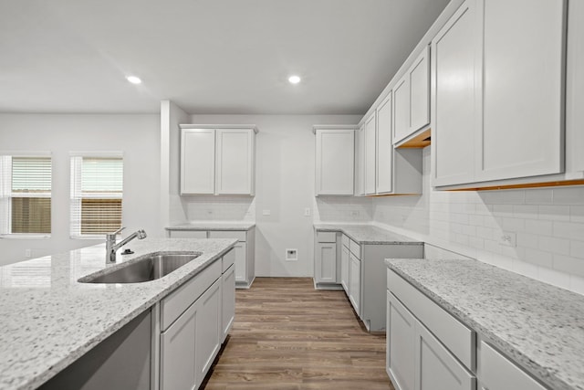 18523 Lilliput Ln, New Caney, TX 77357 - kitchen featuring a sink, light stone countertops, wood finished floors, tasteful backsplash, and recessed lighting