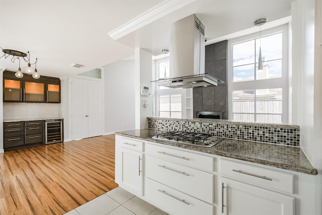 1326 Forest Home Dr, Houston, TX 77077 - kitchen featuring island range hood, wine cooler, stainless steel gas stovetop, tasteful backsplash, and white cabinets