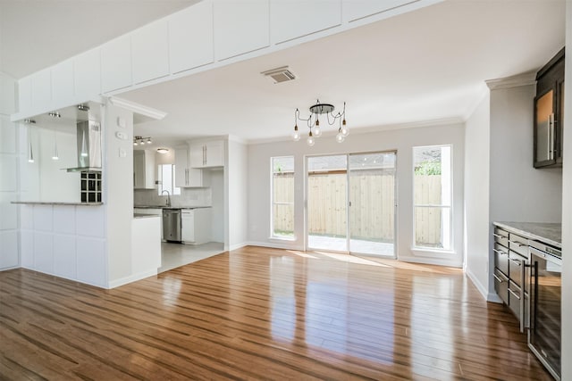 1326 Forest Home Dr, Houston, TX 77077 - unfurnished living room featuring wine cooler, wood finished floors, ornamental molding, a chandelier, and baseboards