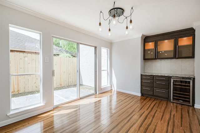 1326 Forest Home Dr, Houston, TX 77077 - unfurnished dining area with beverage cooler, wood finished floors, a chandelier, ornamental molding, and baseboards