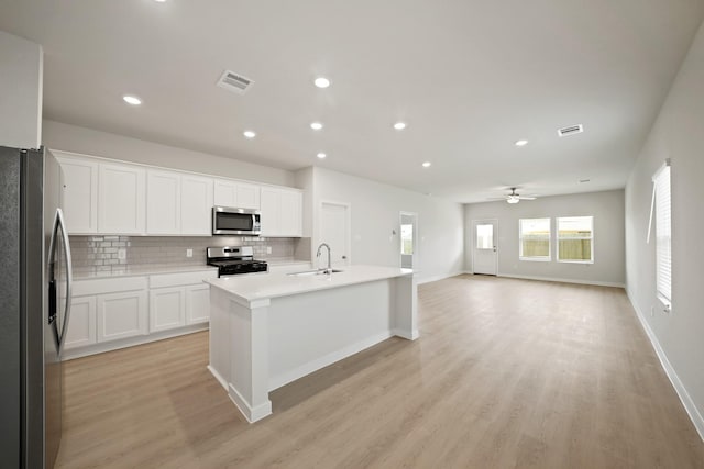 7919 Grand Louis Way, Spring, TX 77379 - kitchen featuring appliances with stainless steel finishes, tasteful backsplash, light wood-style flooring, recessed lighting, and a kitchen island with sink