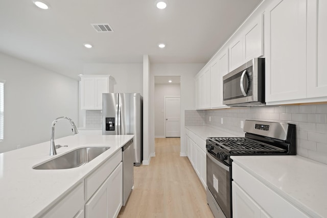 7919 Grand Louis Way, Spring, TX 77379 - kitchen with appliances with stainless steel finishes, light wood-type flooring, backsplash, white cabinetry, and recessed lighting