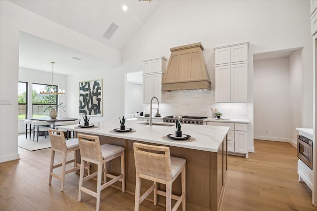 403 Venado View Ct, Conroe, TX 77304 - kitchen featuring custom range hood, a sink, tasteful backsplash, light wood finished floors, and high vaulted ceiling