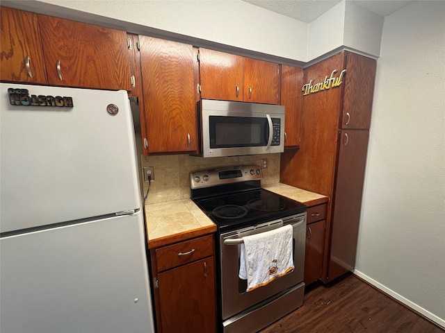 2822 S Bartell Dr Unit 22, Houston, TX 77054 - kitchen featuring stainless steel appliances, tile countertops, dark wood finished floors, decorative backsplash, and baseboards