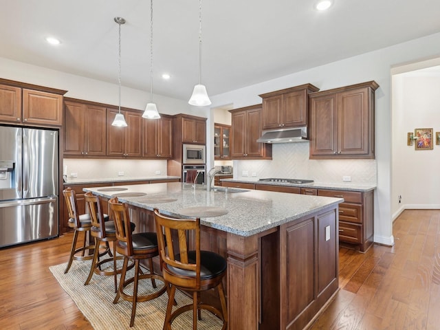27419 Haywood Ln, Katy, TX 77494 - kitchen featuring appliances with stainless steel finishes, under cabinet range hood, a sink, dark wood-style flooring, and recessed lighting