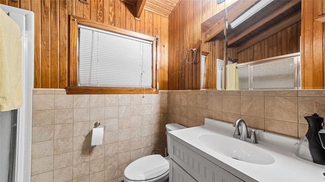 1417 8th St, San Leon, TX 77539 - bathroom featuring toilet, a shower stall, vanity, wood walls, and tile walls