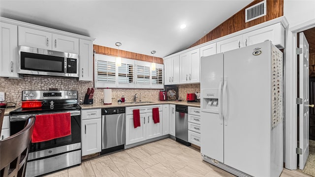 1417 8th St, San Leon, TX 77539 - kitchen with stainless steel appliances, lofted ceiling, white cabinetry, tasteful backsplash, and light countertops