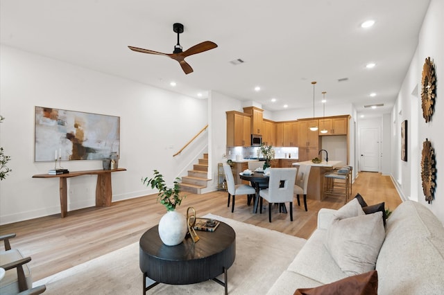 6705 Del Rio St, Houston, TX 77021 - living room featuring stairway, light wood-style flooring, a ceiling fan, recessed lighting, and baseboards