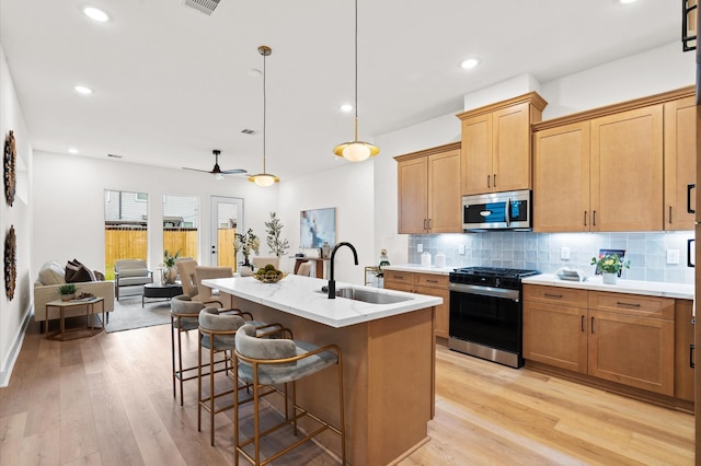 6705 Del Rio St, Houston, TX 77021 - kitchen with gas range oven, stainless steel microwave, a sink, tasteful backsplash, and light wood-style flooring