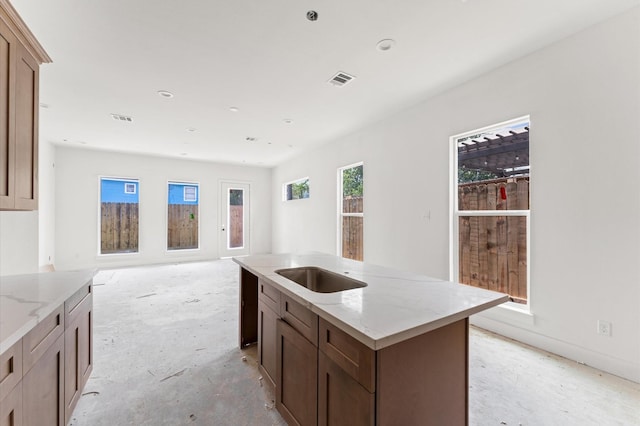 6705 Del Rio St, Houston, TX 77021 - kitchen featuring a center island with sink, light stone countertops, open floor plan, and concrete floors